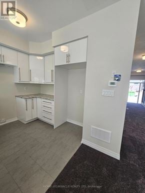 Brantford townhouse for rent - A real estate photo of a kitchen area with white cabinets and a grey floor.
