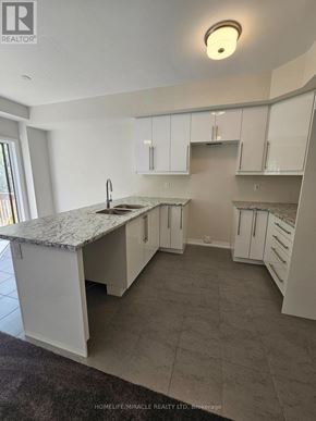 Brantford townhouse for rent - A kitchen with white cabinets and a marble countertop.
