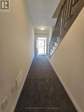 Brantford townhouse for rent - A hallway with a carpeted floor and a staircase on the right side.