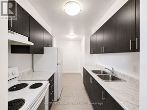Toronto (Victoria Village) condo for rent - A kitchen with black cabinets and white appliances.