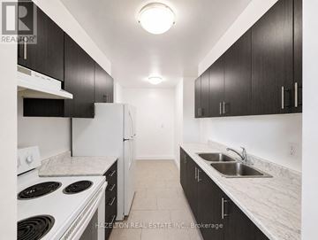 Toronto (Victoria Village) condo for rent - A kitchen with black cabinets and white appliances.