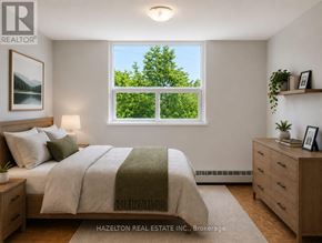 Toronto (Victoria Village) condo for rent - A bedroom with a bed, nightstand, and a window with a view of trees.