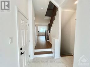 Ottawa townhouse for rent - A hallway with a wooden staircase and white walls.