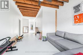 Toronto (Little Portugal) apartment for rent - A living room with a grey couch and a wooden beam ceiling.