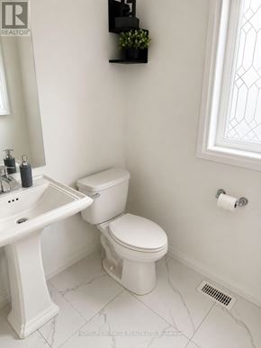 Brantford apartment for rent - A white toilet sits next to a sink in a bathroom.