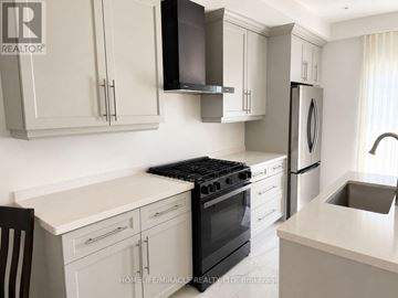 Brantford apartment for rent - A kitchen with white cabinets and black appliances.
