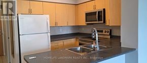 Toronto (Lansing-Westgate) condo for rent - A kitchen with a white fridge and a black counter top.