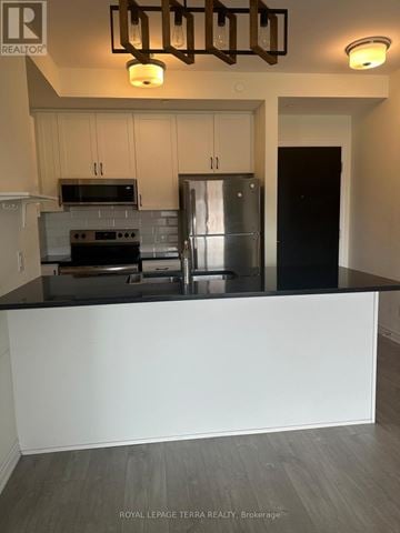 Brampton (Credit Valley) condo for rent - A kitchen with a stove top oven, microwave, and refrigerator.