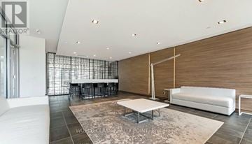 Burlington (Orchard) condo for rent - A modern living room with a white sofa and a glass partition wall.
