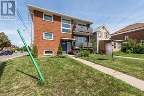 Toronto (Mimico) triplex for rent - A green pole stands in the front yard of a brick house.