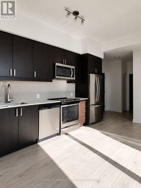 Mississauga (Hurontario) condo for rent - A modern kitchen with black cabinets and stainless steel appliances.