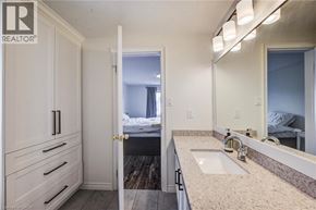 Kitchener apartment for rent - A bathroom with a sink, mirror, and a bedroom in the background.