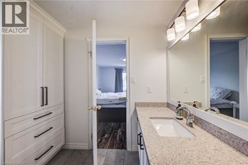 Kitchener apartment for rent - A bathroom with a sink, mirror, and a bedroom in the background.