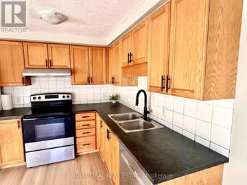 Waterloo townhouse for rent - A kitchen with wooden cabinets and a black stove top oven.