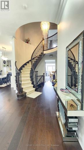 Brampton (Credit Valley) apartment for rent - A large, elegant staircase with a chandelier and a mirror on the wall.