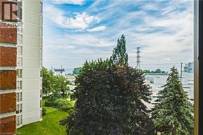 Burlington condo for rent - A view from a window of a green tree, a building and a power line.