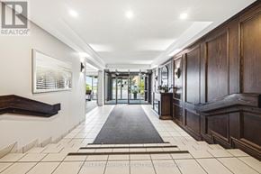 Burlington (Brant) condo for rent - A hallway with a black and white tiled floor, a grey runner, and a wooden door.