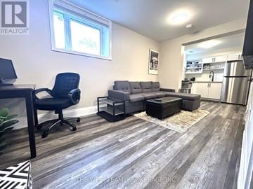 Toronto (East End-Danforth) apartment for rent - A well-lit living room with a grey sofa and a black chair.
