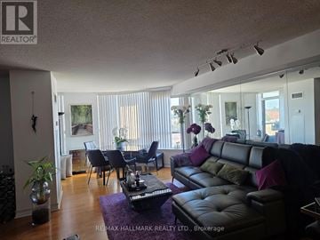 Richmond Hill (Beaver Creek Business Park) condo for rent - A living room with a black leather couch and a dining table with chairs.