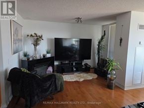 Richmond Hill (Beaver Creek Business Park) condo for rent - A living room with a black couch and a flat screen TV.