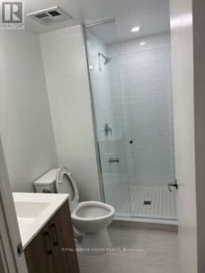 Toronto (Humber Heights) condo for rent - A white toilet in a bathroom with a glass shower door.