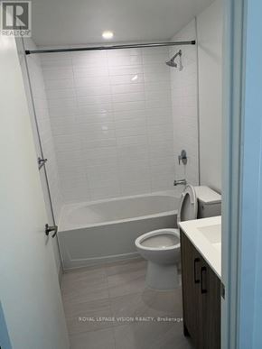 Toronto (Humber Heights) condo for rent - A white tiled bathroom with a toilet, sink, and bathtub.