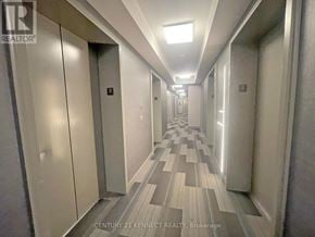 Toronto (Moss Park) condo for rent - A long hallway with a tiled floor and white walls.