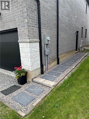 Hamilton apartment for rent - A grey brick building with a black door and a grey stone walkway.