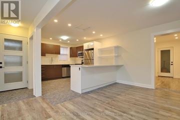 Ottawa triplex for rent - A spacious kitchen with white cabinets and a wooden floor.