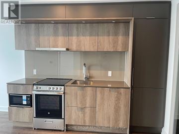 Mississauga (City Centre) condo for rent - A modern kitchen with wooden cabinets and stainless steel appliances.