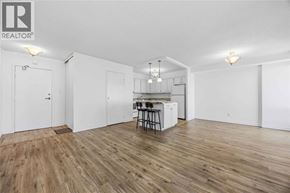 Sarnia condo for rent - A room with wooden flooring and white walls, featuring a kitchenette with a sink and bar stools.