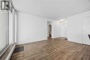 Sarnia condo for rent - A spacious room with wooden flooring and white walls.