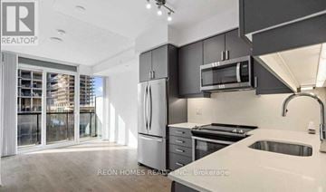 Vaughan (Concord) condo for rent - A modern kitchen with a refrigerator, microwave, and stove top oven.