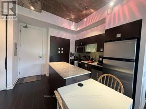 Toronto (Waterfront Communities) condo for rent - A kitchen with a table and chairs in the foreground and a refrigerator in the background.