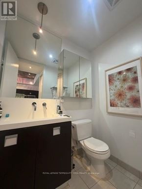 Toronto (Waterfront Communities) condo for rent - A bathroom with a toilet, sink, and mirror.