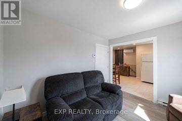 The Nation triplex for rent - A living room with a grey sofa and a lamp on a side table.