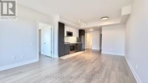 Toronto (Forest Hill North) condo for rent - A spacious living room with a kitchen in the background.