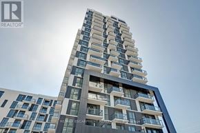 Oakville (Jm Joshua Meadows) condo for rent - A tall building with a modern design and balconies on the upper floors.