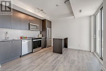 Oakville (Jm Joshua Meadows) condo for rent - A modern kitchen with dark wood cabinets and stainless steel appliances.