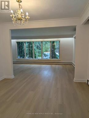 Toronto (Bayview Village) apartment for rent - A room with a chandelier and a window with a view of trees.