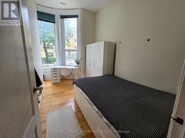 Toronto (Kensington-Chinatown) multi-family for rent - A bedroom with a bed, dresser, and window.