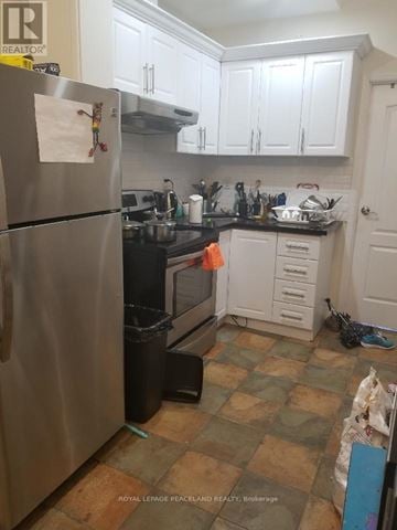 Toronto (Kensington-Chinatown) multi-family for rent - A kitchen with a refrigerator, sink, and cabinets.