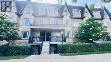 Markham (Aileen-Willowbrook) townhouse for rent - A large, multi-level house with a stone facade and a black metal fence.