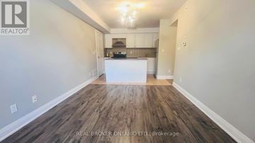 Markham (Aileen-Willowbrook) townhouse for rent - A spacious room with wood flooring and a kitchenette in the background.