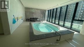 Toronto (North St. James Town) condo for rent - A swimming pool in a room with a stone wall and a couch.