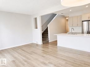Edmonton apartment for rent - A spacious kitchen with a refrigerator, sink, and cabinets.