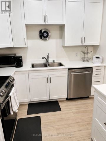 Prince Edward County (Picton Ward) townhouse for rent - A kitchen with white cabinets and a stainless steel dishwasher.