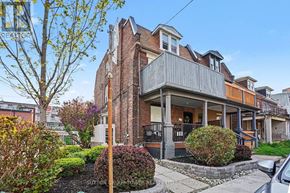 Toronto (Junction Area) apartment for rent - A house with a brick facade and a balcony is surrounded by greenery.