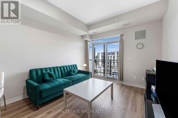 St. Catharines (Oakdale) condo for rent - A living room with a green couch and a glass door leading to a balcony.