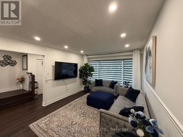 Mississauga (Erin Mills) apartment for rent - A living room with a grey couch and a television on the wall.
